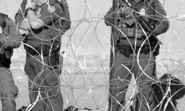 Image showcasing border police behind barbed wires.